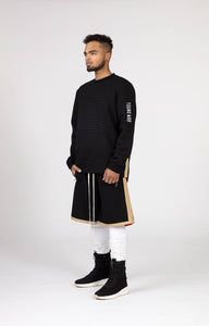 Black Male model wears mens black and gold casual summer fashion long shorts silk lined for our menswear blog and magazine photography side view